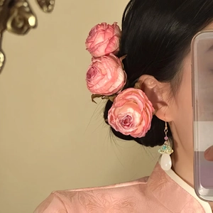 Detail shot showing realistic pink fabric rose hair pins styled in a dark hair bun
