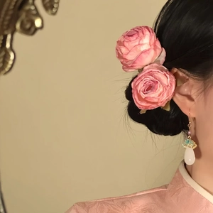 Close-up of a model wearing elegant pink fabric rose hair accessories and drop earrings