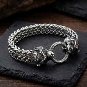 Detailed close-up of vintage wolf head steel bracelet on dark stone and wood background