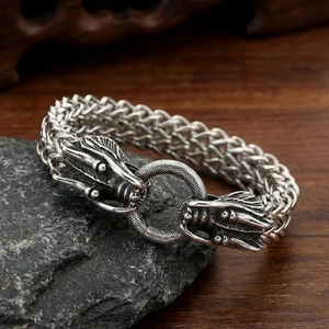 Close-up of vintage braided steel bracelet featuring detailed dragon head metal clasps