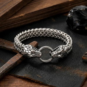 Detailed view of dual snake head vintage stainless steel braided bracelet on rustic background