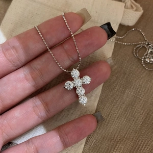 Close-up detail of a sparkling zirconia cross pendant necklace on a silver chain