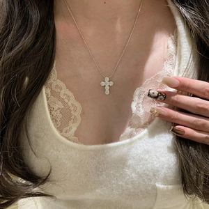 Elegant detail shot of a sparkling zircon cross pendant necklace worn on a model's neck.