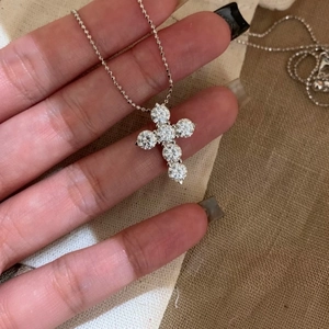 Close-up of a sparkling zircon cross pendant necklace on a silver ball chain