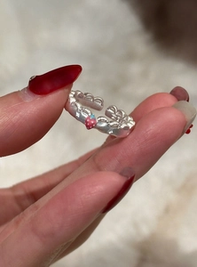 Vista macro dettagliata di un anello in pizzo d'argento con ciondoli fragola e stella