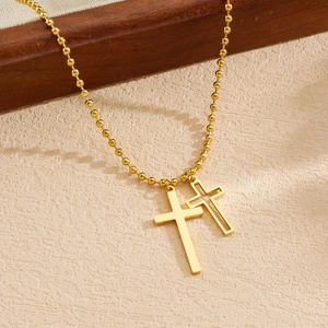 Detail of gold-plated stainless steel necklace with solid and hollow cross pendants.