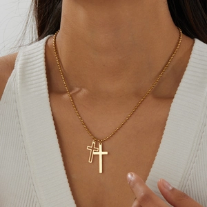 Detail shot of a gold-plated stainless steel bead chain necklace with double cross pendants.