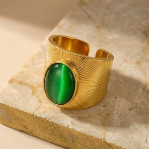 Dettaglio macro di anello vintage in oro con trama radiale e pietra occhio di gatto verde
