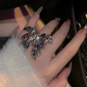Close-up detail of a silver butterfly ring with wrinkled texture and blue enamel