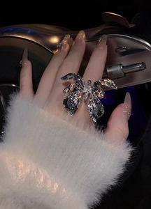 Detailed shot of a silver butterfly wrinkled open ring on a hand with luxury manicured nails