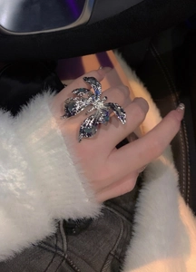 Macro view showing a wrinkled silver butterfly open ring worn on an index finger