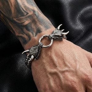 Detail of vintage dragon head bracelet featuring a round clasp on black leather background