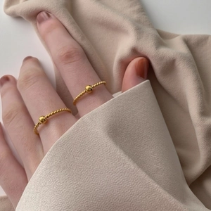 Primo piano di eleganti anelli in acciaio al titanio placcato oro 18K con perlina