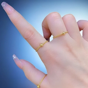 Primo piano di eleganti anelli a corda dorata con piccole perline sulla mano di una donna