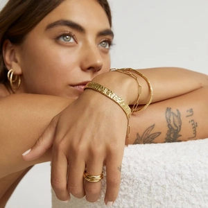 Détail du jonc ouvert à texture martelée et ensemble de bijoux minimalistes dorés 18K