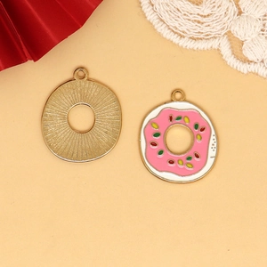 Detailansicht eines rosa Emaille-Donut-Anhängers mit Vorderseite und goldener Rückseite