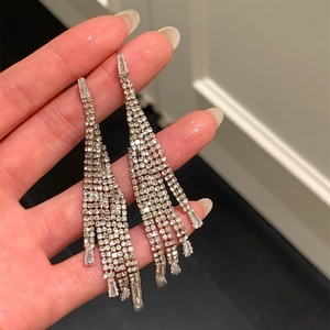Gros plan de boucles d'oreilles à pompons en strass étincelants tenues à la main
