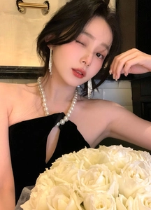 Élégante mannequin asiatique portant de longues boucles d'oreilles à pompons scintillants