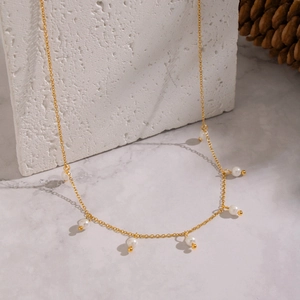 Detail of 18K gold plated necklace with delicate dangling white pearls on stone
