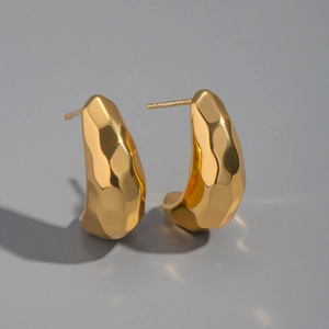 Gros plan sur des boucles d'oreilles dorées avec texture martelée et métal liquide