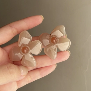 Close-up of retro French acrylic flower earrings in translucent tea-jelly brown.