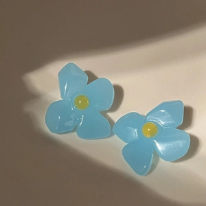 Close-up of French retro blue acrylic flower earrings with yellow centers