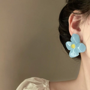 Close-up detail of a light blue acrylic flower earring featuring a vintage French design