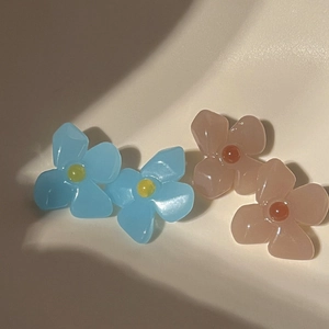 Close-up detail of retro acrylic flower earrings in pastel blue and peach jelly colors