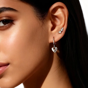 Macro detail of tiny s925 silver heart screw earrings and stud set on a model