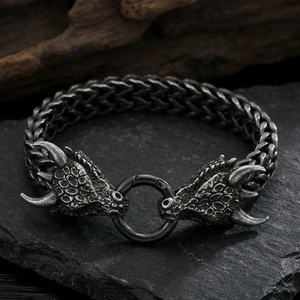 Detail of vintage dragon head titanium steel bracelet on black rock background