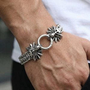 Detailed view of vintage steel dragon head links on a braided motorcycle bracelet
