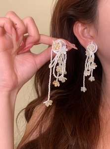 Detailed macro shot of white floral beaded tassel earrings for a sweet spring vacation look.