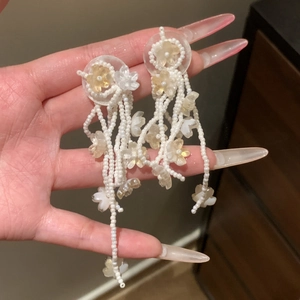 Detailed view of handmade beaded tassel earrings with elegant white and yellow flowers