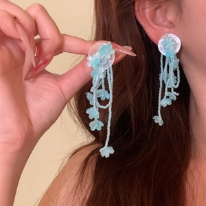 Detailed macro view of blue beaded floral tassel earrings for a sweet vacation look.