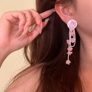 Close-up of pink floral beaded tassel earrings worn by a model for a sweet vacation look