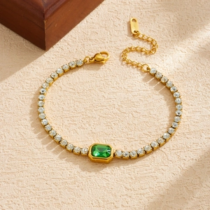 Detailed macro view of gold plated tennis bracelet with green emerald cut cubic zirconia stone