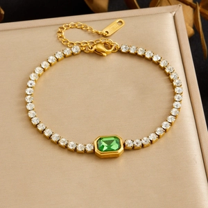 Macro detail of a gold-plated stainless steel bracelet with green and clear zircon stones