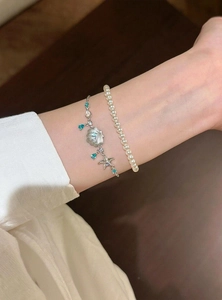 Detaillierte Nahaufnahme von Seestern- und Muschelarmband mit blauen Charms und Perlen