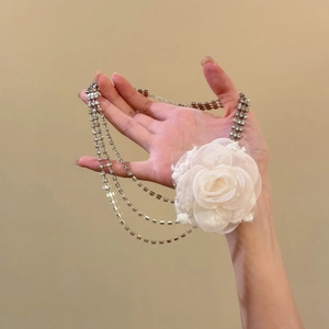 Dettaglio di un girocollo multistrato con strass e un grande fiore in chiffon bianco