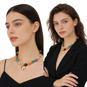 Dettaglio di una collana di perle in resina colorata con ciondolo a cuore dorato lucido