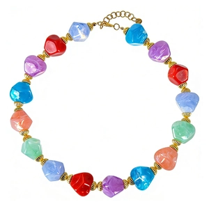 Collana di perle in resina colorata con ciondolo a cuore dorato su sfondo bianco.