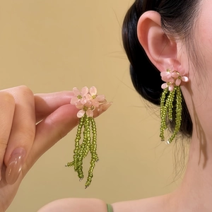 Detailed view of pink beaded flower stud earrings with green seed bead tassels