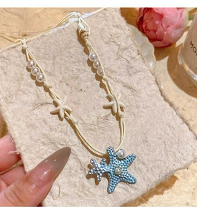 Detailed view of ocean-themed necklace with blue starfish pendants and pearl accents.