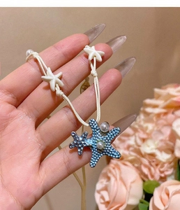 Detailed view of blue textured starfish pendant necklace with pearls on white cord