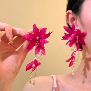 Detailed view of oversized fuchsia fabric flower tassel earrings for bohemian beach style.