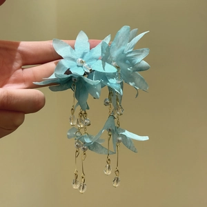 Hand holding light blue fabric flower tassel earrings with faux pearls and beads
