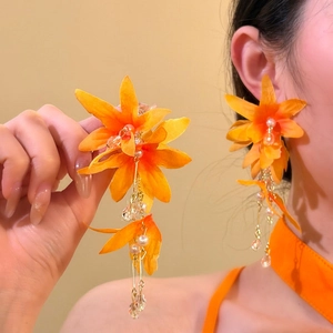 Detailed view of long orange fabric flower earrings with pearl tassels and crystals