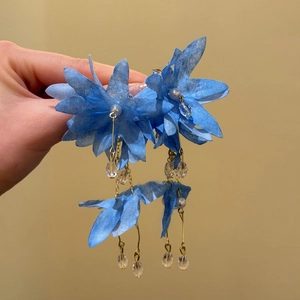 Detail shot of elegant blue fabric flower tassel earrings with delicate crystal beads