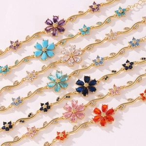 Close-up of golden vine bracelets with multi-colored floral stones and leaf accents