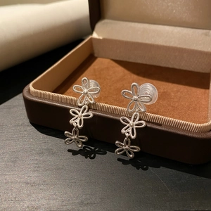 Detailansicht silberner Vintage-Ohrclips mit hohlem Blumen-Tassel-Design in einer Schmuckschatulle